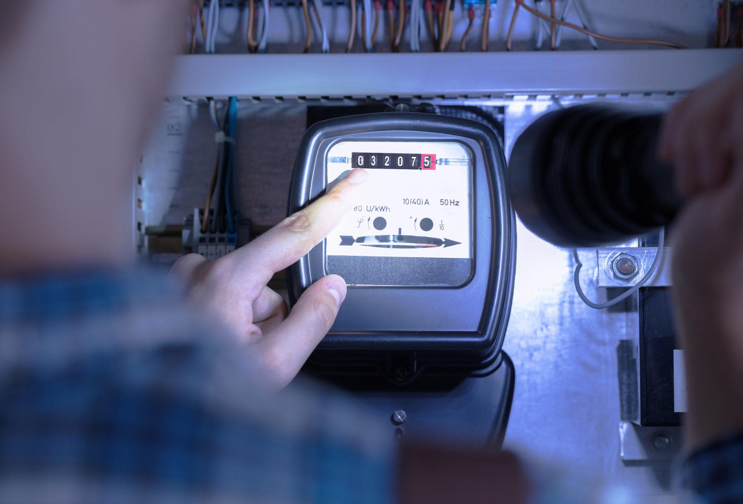 Mann liest Stromzähler ab
